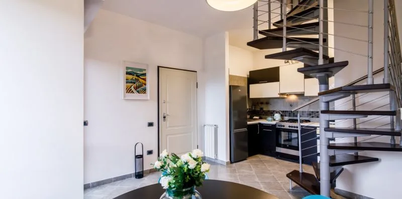 A bright open-plan room with a kitchen and a spiral staircase.