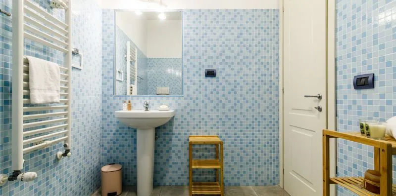 A tiled bathroom with a sink, mirror, and towel warmer.