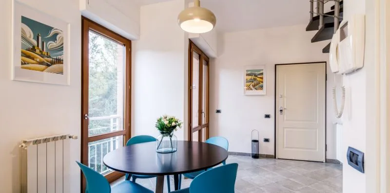 A bright dining area with a round table, blue seating, and a large window.