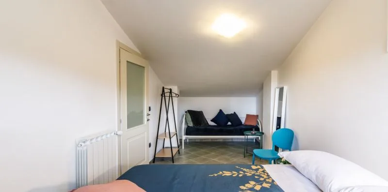 A bedroom with a bed, a radiator, and a small seating area.