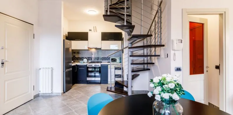 A kitchen and dining area with a table beside a spiral staircase.