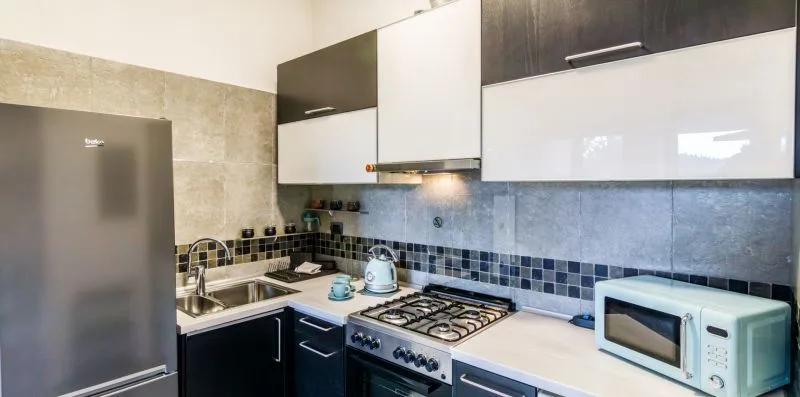 A kitchen with dark cabinets, a refrigerator, and countertop appliances.
