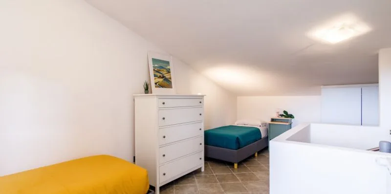 A bright bedroom with a bed, dresser, and white built-in tub.
