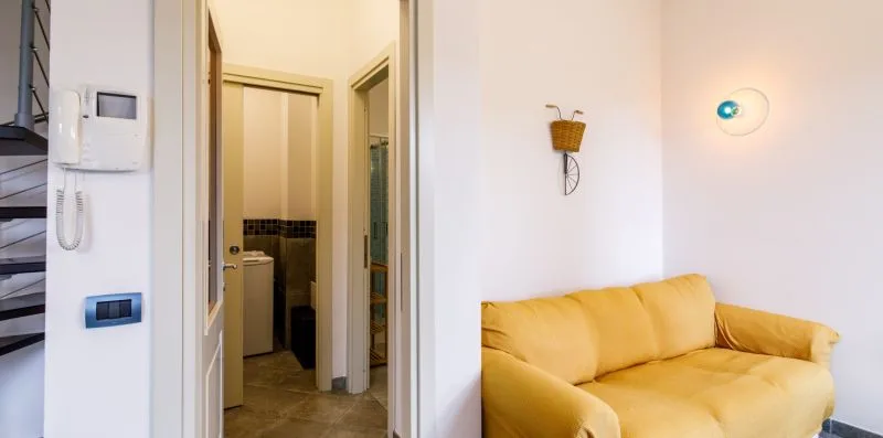 A living room with yellow seating beside an open doorway.
