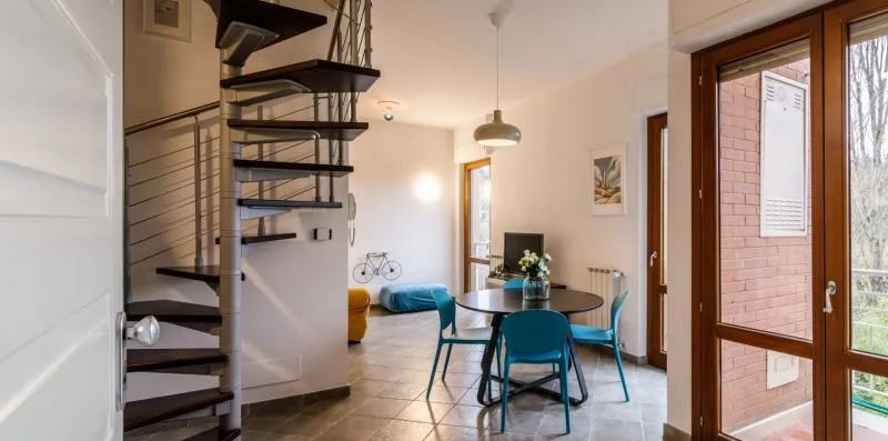 Un comedor abierto con una mesa redonda y una escalera de caracol.