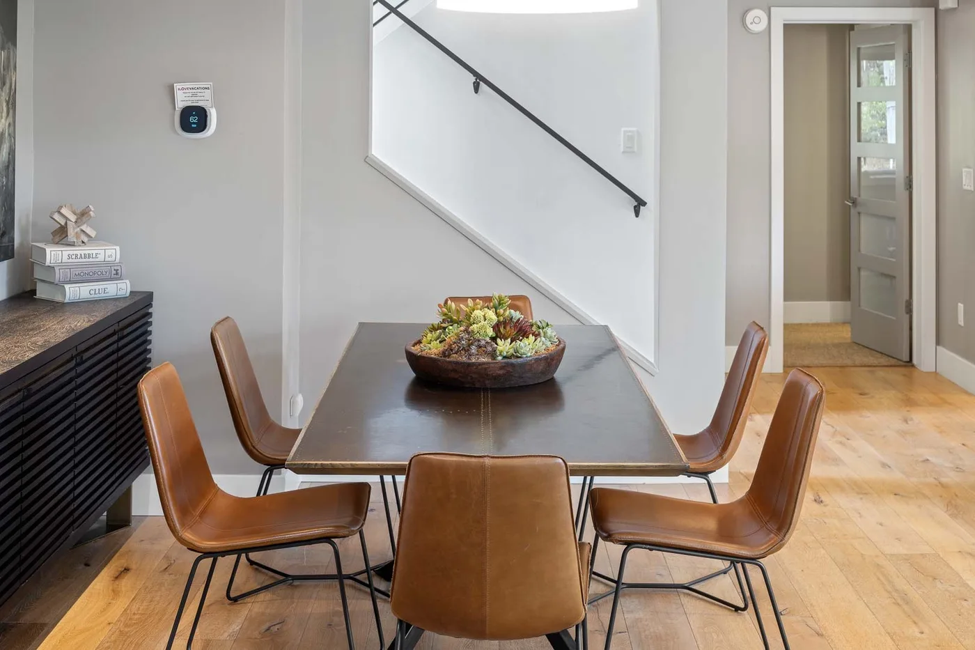 A dining area with a dark table, brown seating, and a bowl of fruit.