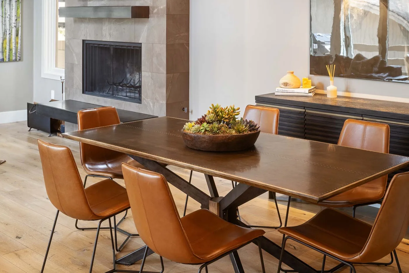 A dining area with a wooden table and brown seating beside a fireplace.