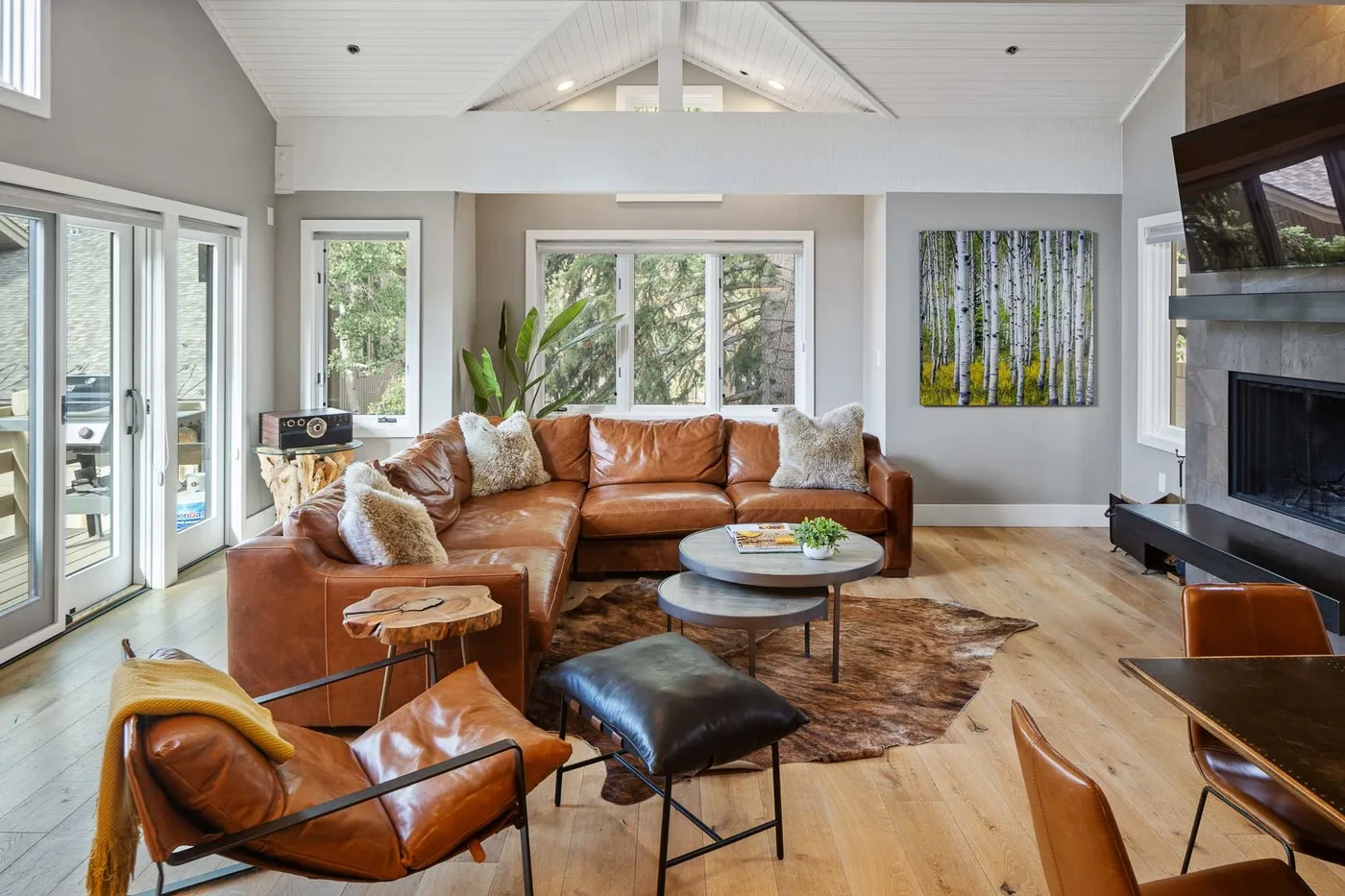 A bright living room with leather seating, a coffee table, and a large fireplace.