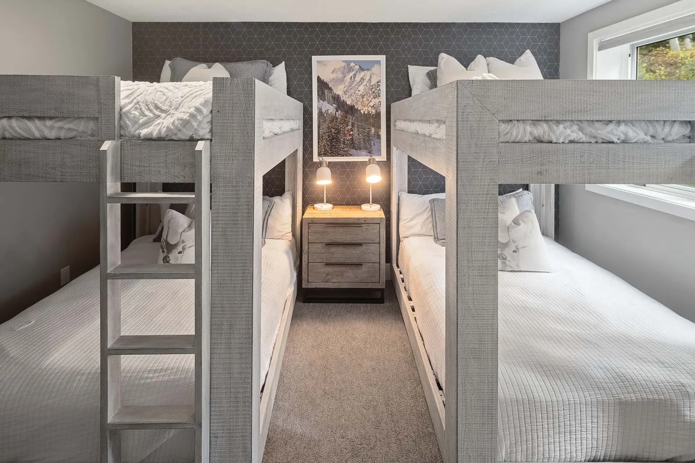 A bedroom with two bunk beds and a nightstand between them.