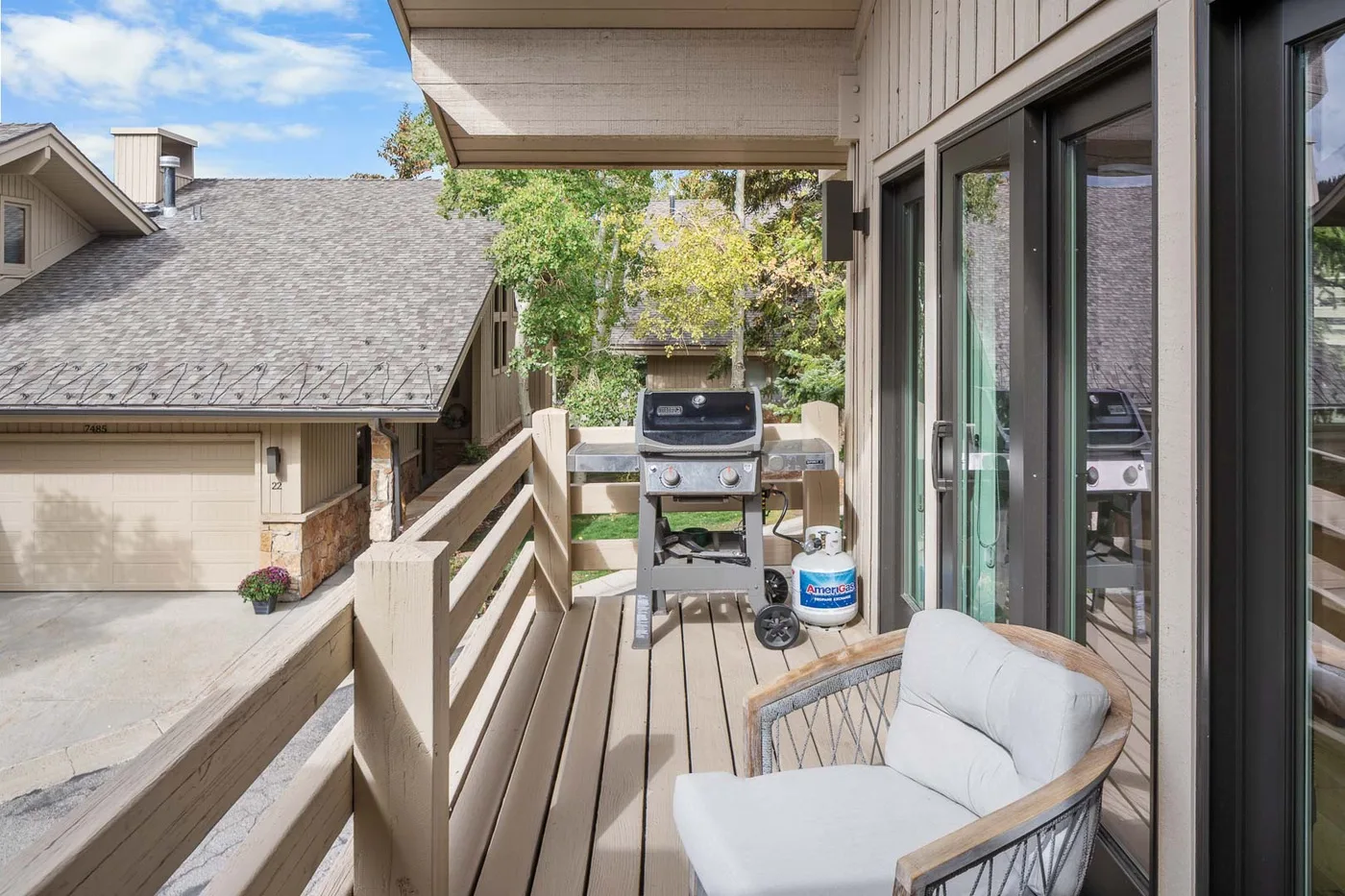 A wooden deck with a barbecue grill and cushioned outdoor seating.