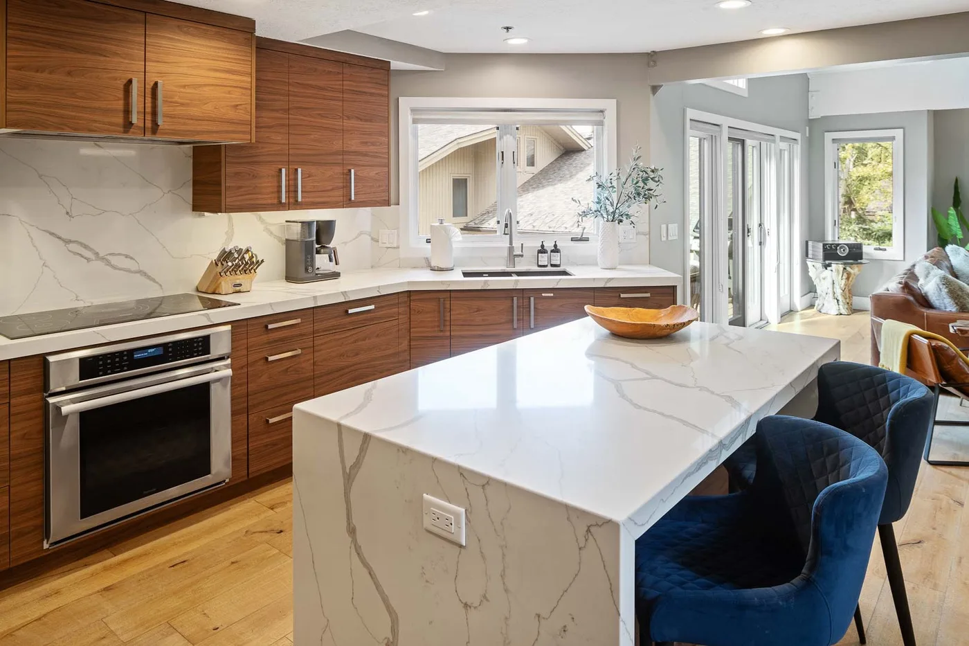 A modern kitchen with wood cabinets and a large marble-patterned island.