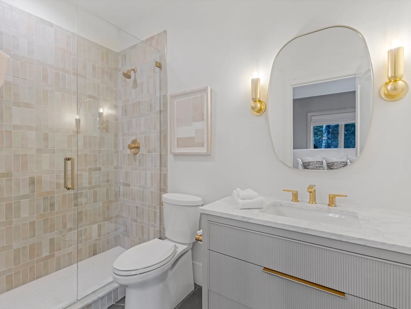 A bright bathroom with a glass-enclosed shower, toilet, and vanity.