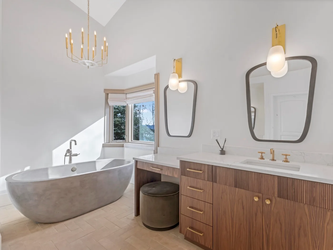 A bright bathroom with a freestanding tub, a window, and a long vanity.