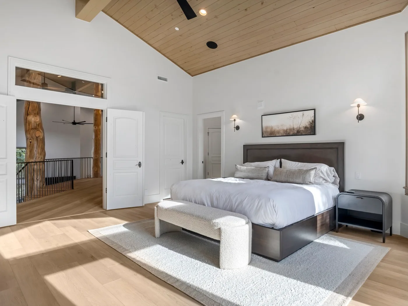 A bedroom with a large bed beneath a sloped wood-paneled ceiling.