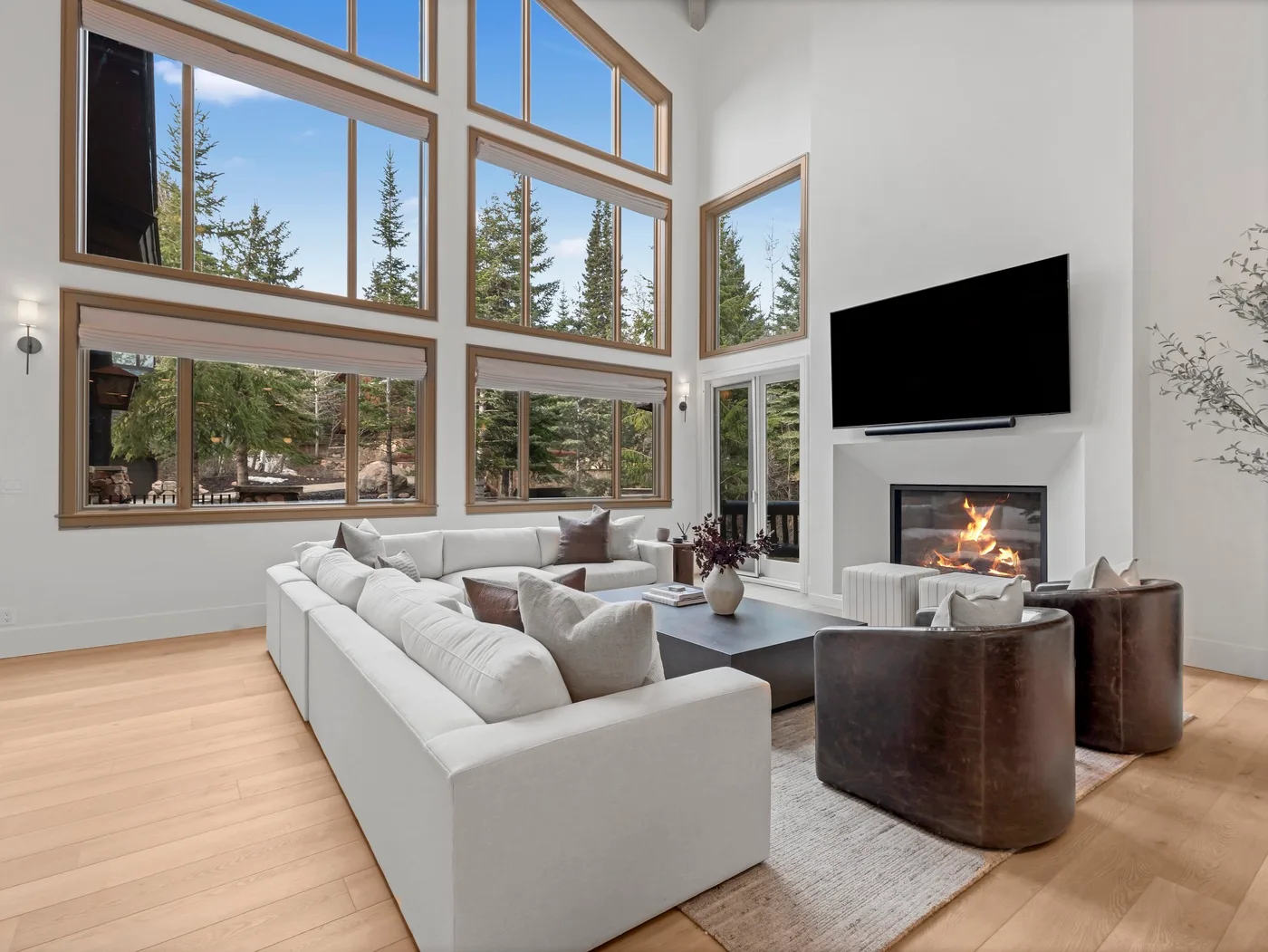 A bright living room with expansive windows, seating, and a fireplace.