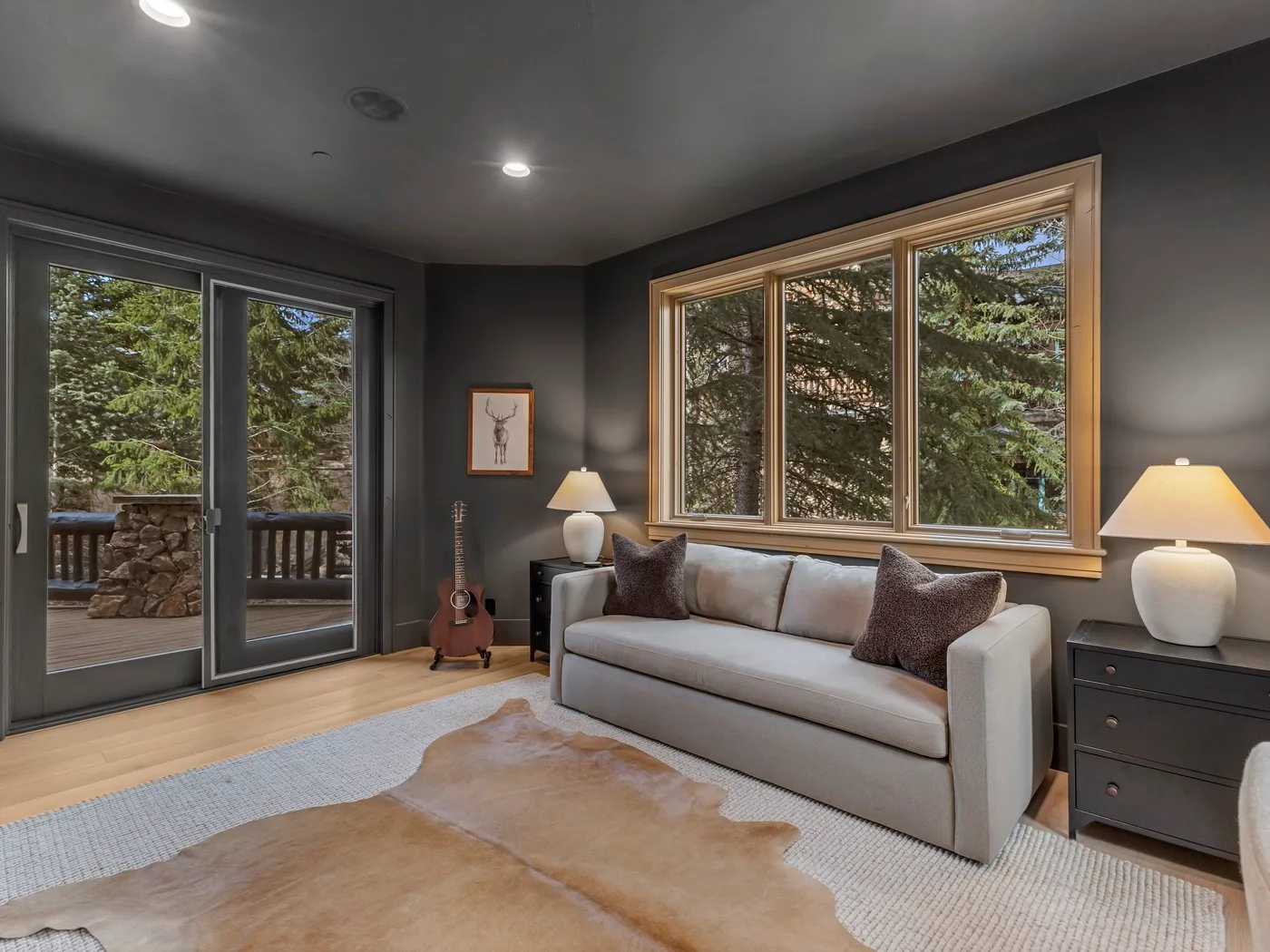 A living room with a sofa beside large windows overlooking trees.