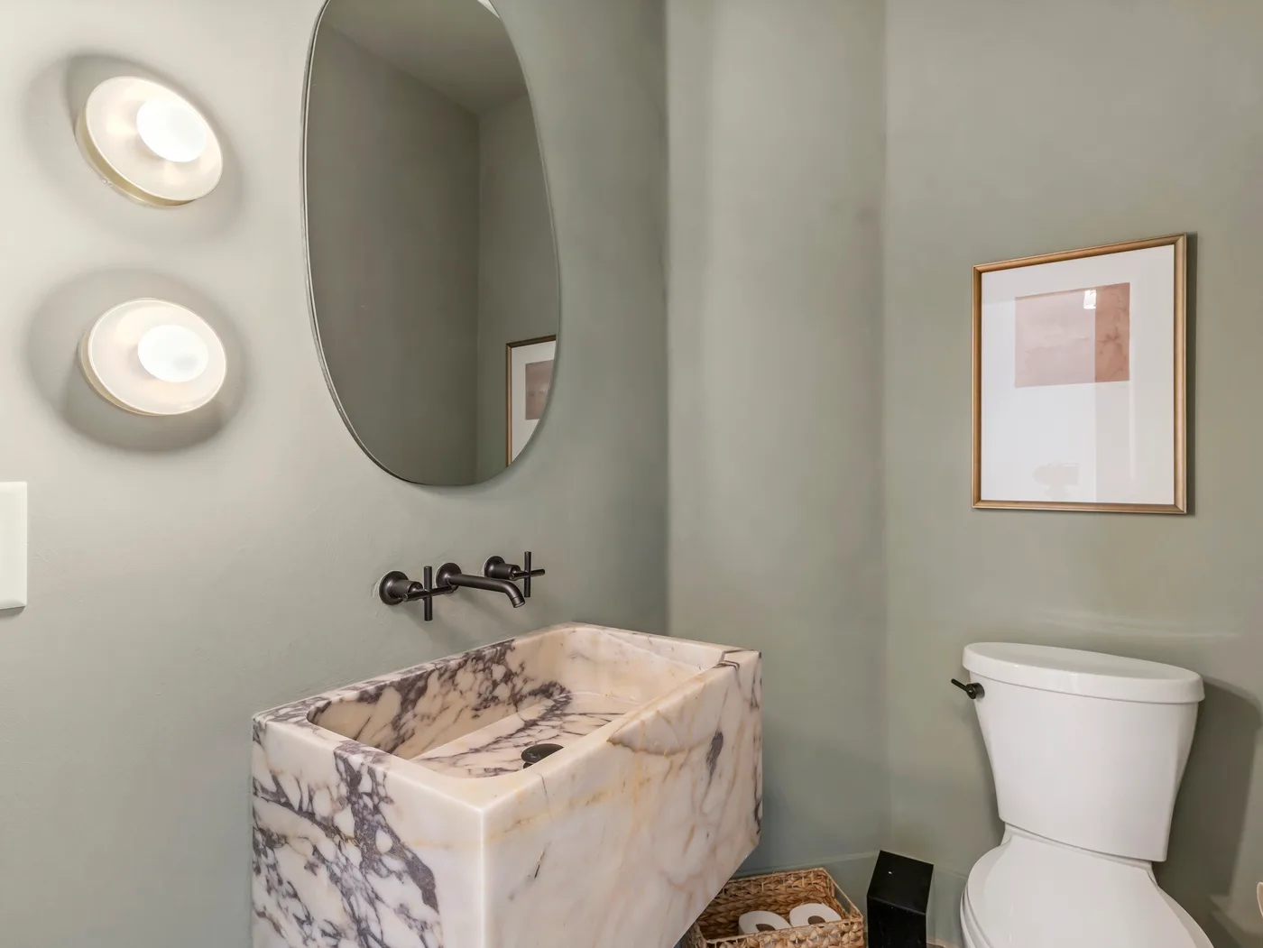 A bathroom with a patterned sink, wall mirror, and toilet.