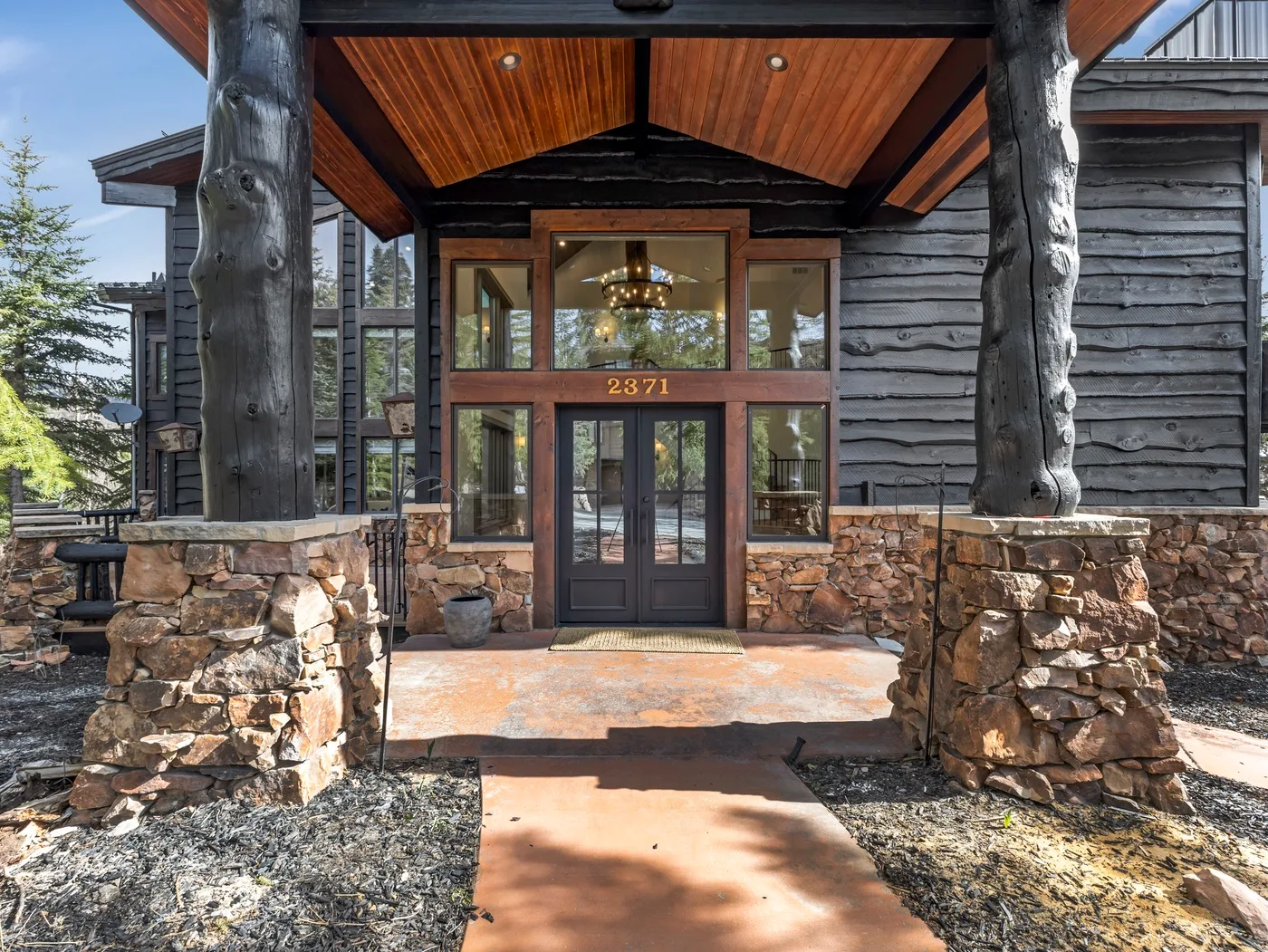 A lodge entrance with glass double doors beneath a timber-and-stone canopy.