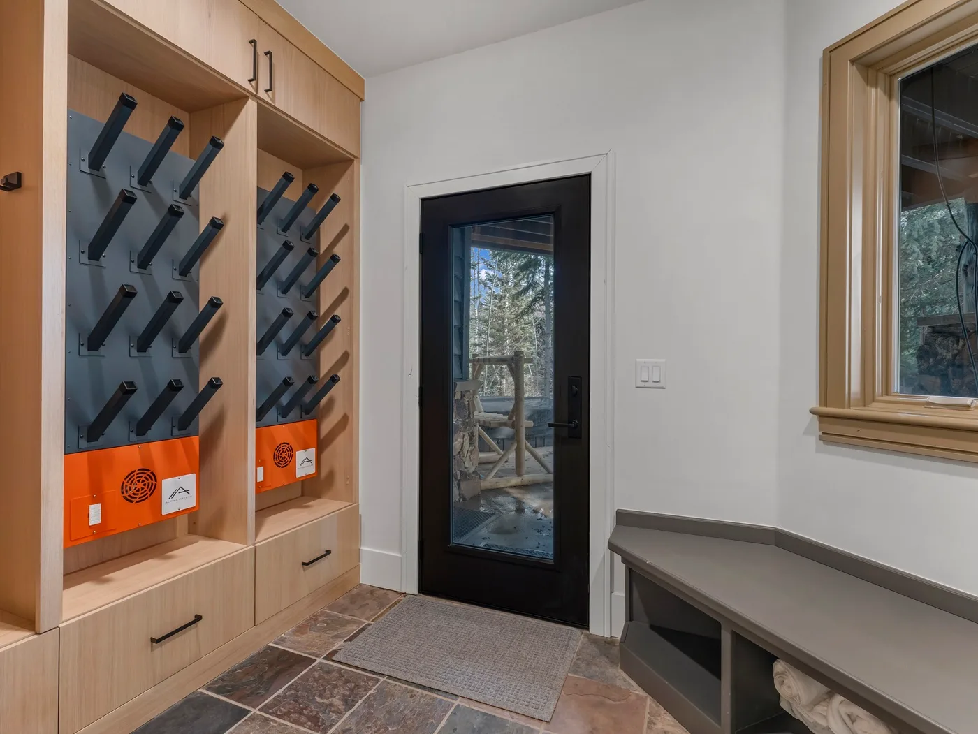 An entryway with built-in storage, a dark glass door, and a bench.