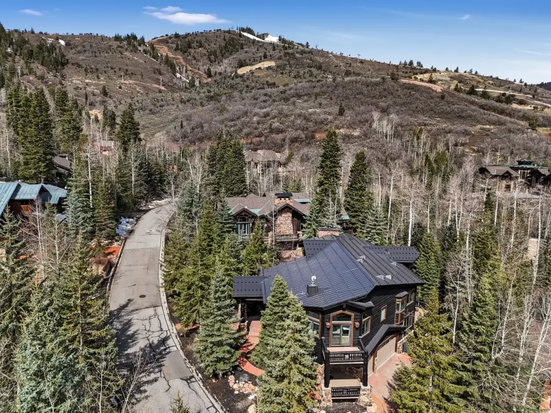 An aerial view of a mountain neighborhood with homes among pine trees.