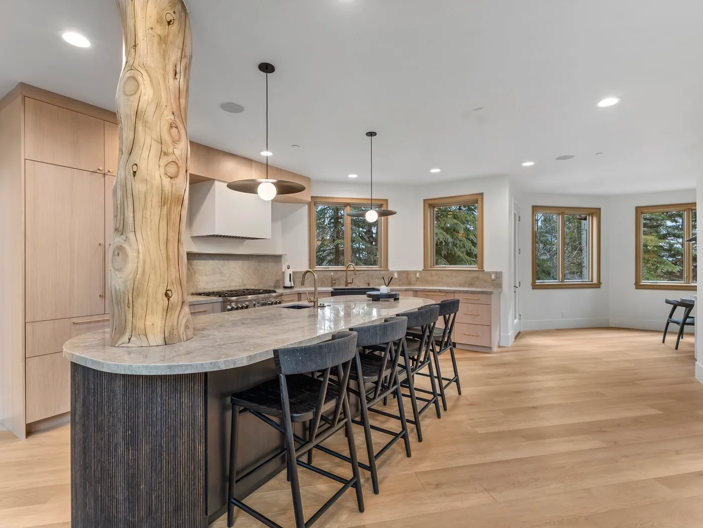A bright kitchen features a long island with seating and large windows.