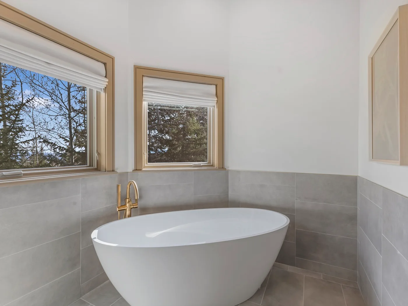 A bathroom features a freestanding bathtub beneath two windows.