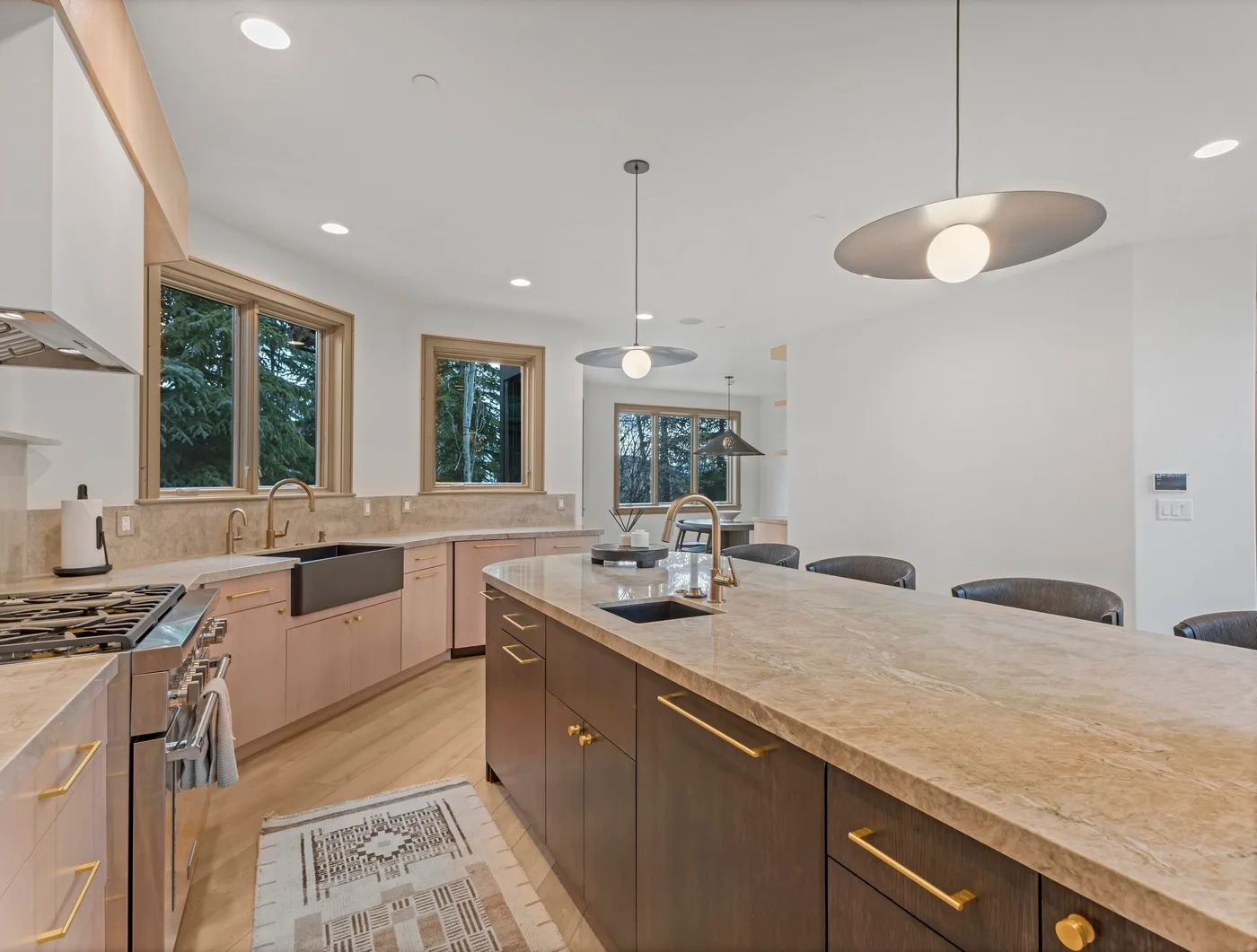 A bright kitchen with a large island, counter seating, and windows overlooking greenery.