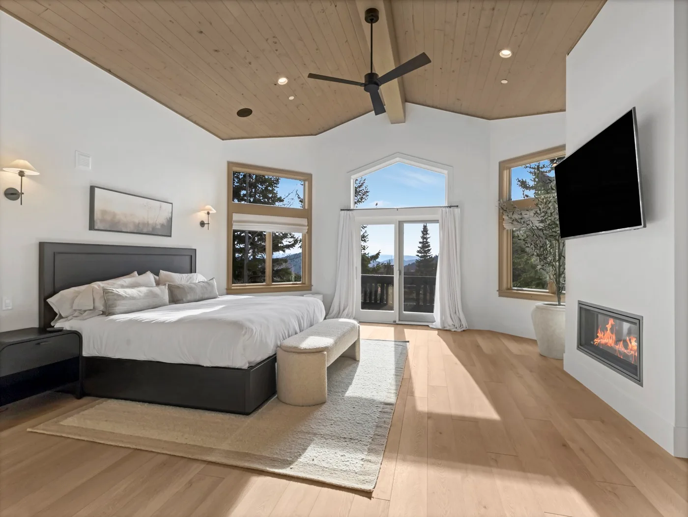A bright bedroom with a bed, large windows, and a ceiling fan.