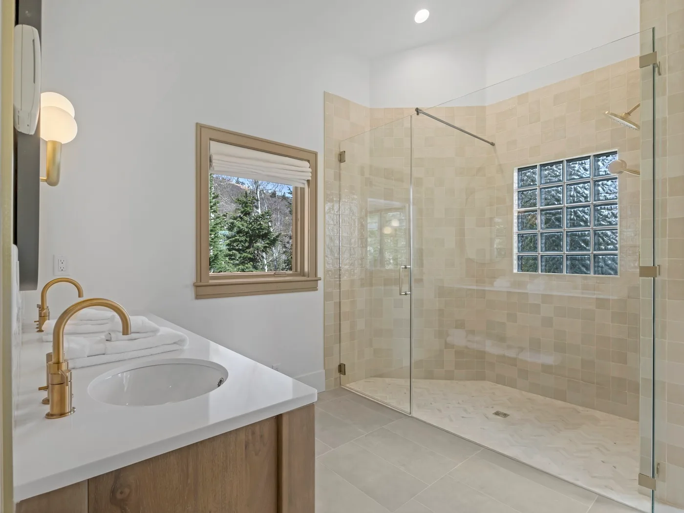 A bright bathroom features a vanity beside a glass-enclosed shower.