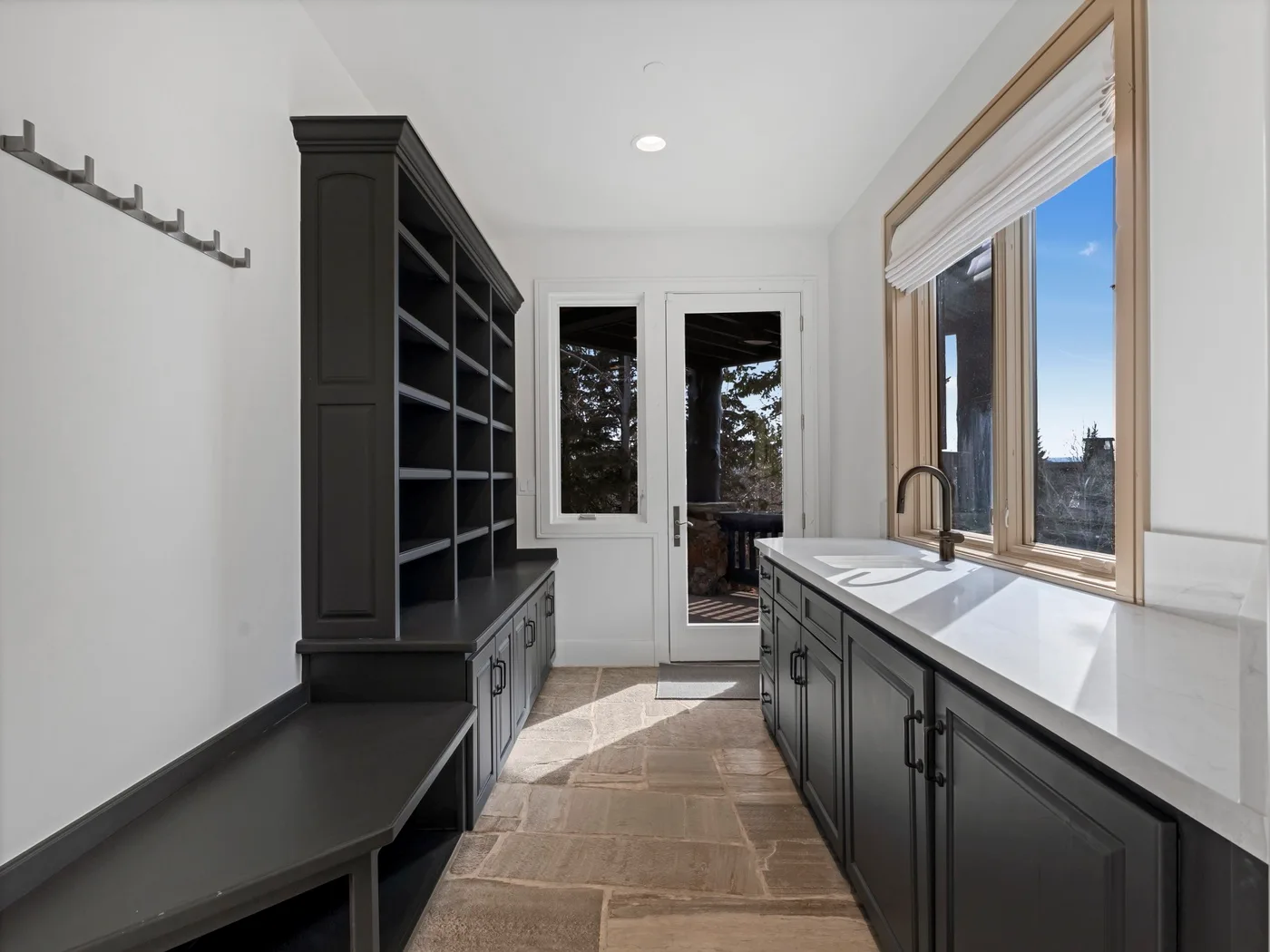 A bright kitchen with dark cabinetry, a long counter, and windows overlooking the outdoors.