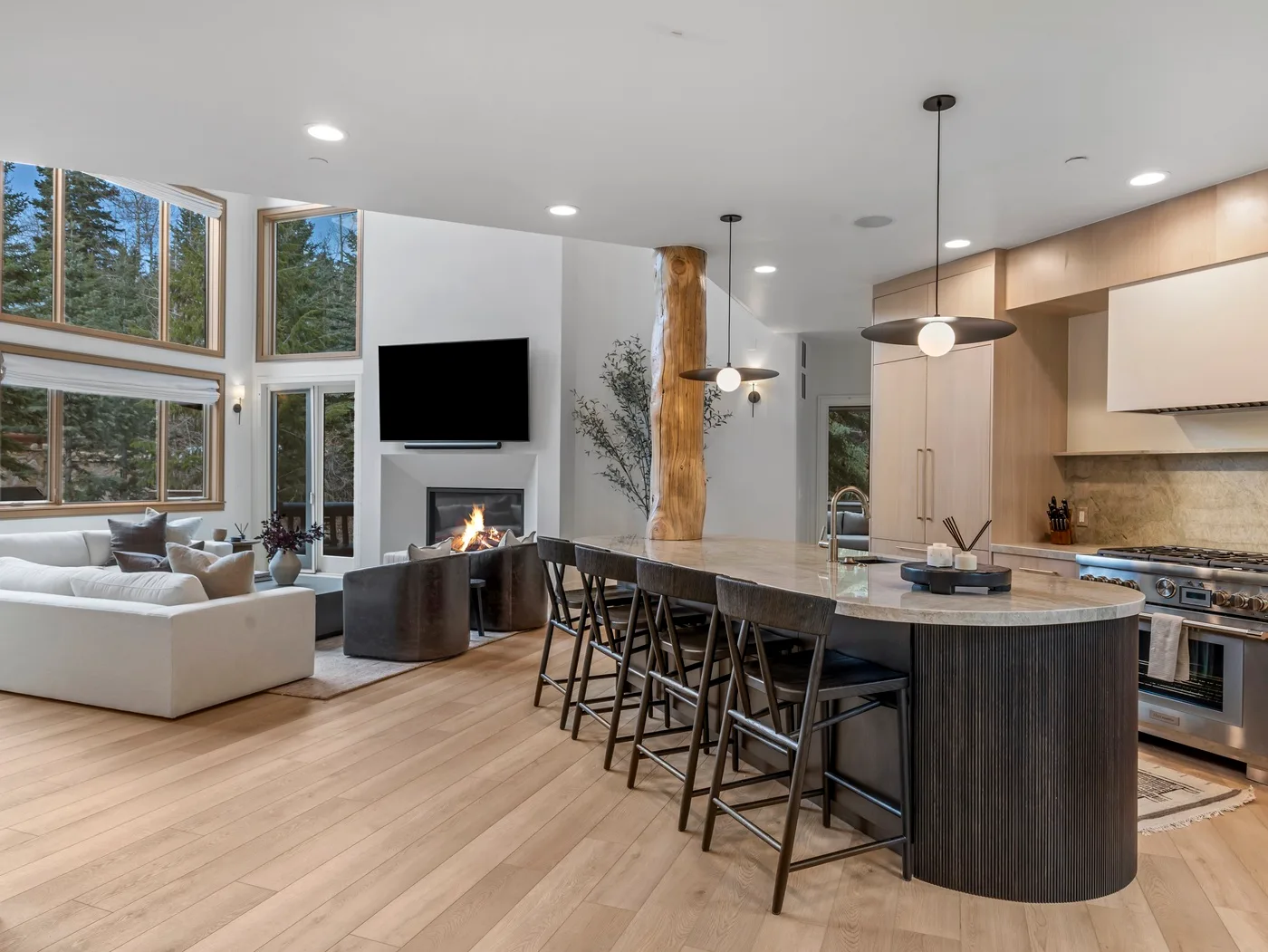 Sala de estar y cocina de concepto abierto, con una isla larga y grandes ventanas.