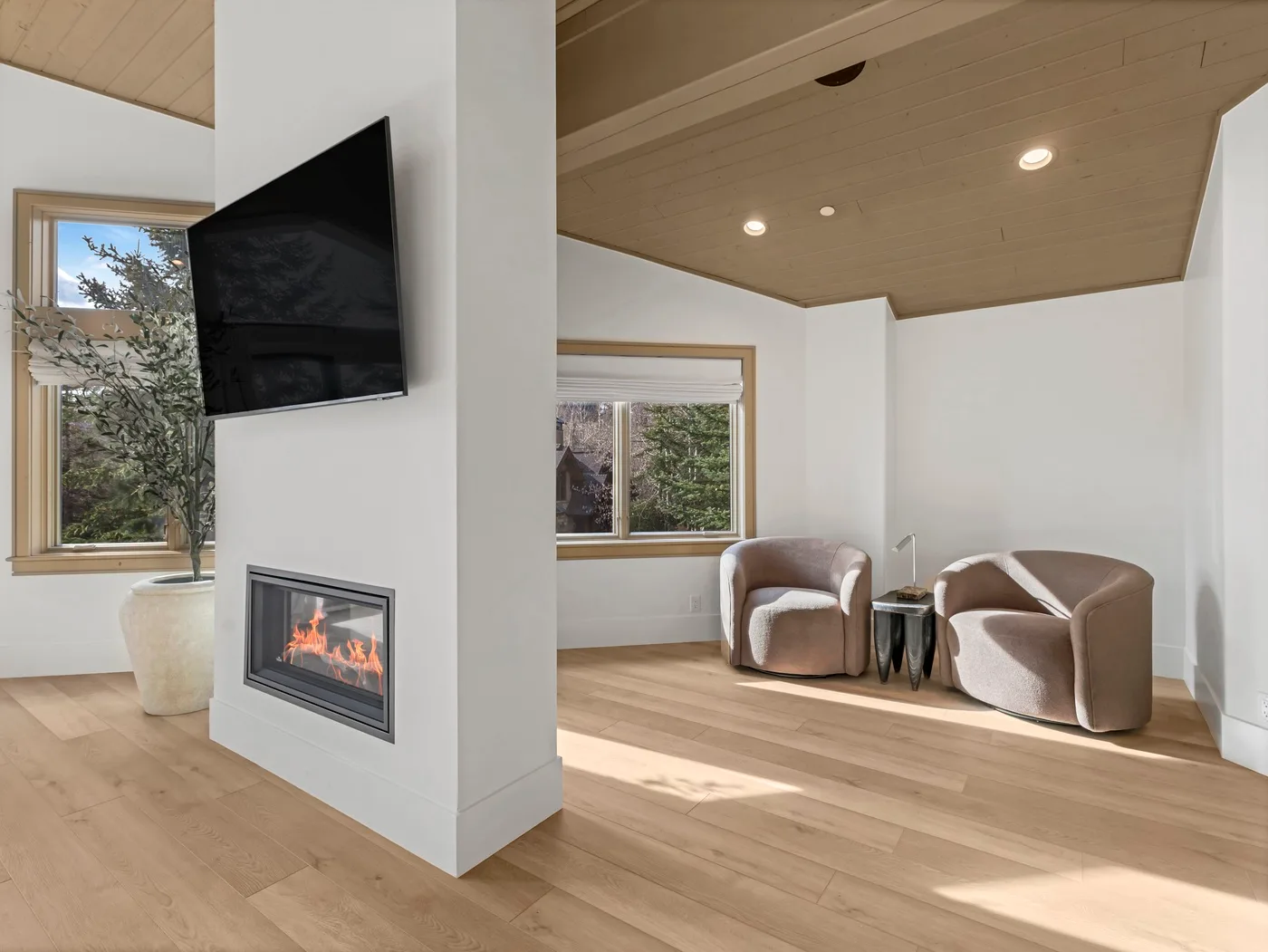 A bright living room with a wall-mounted television, fireplace, and seating.