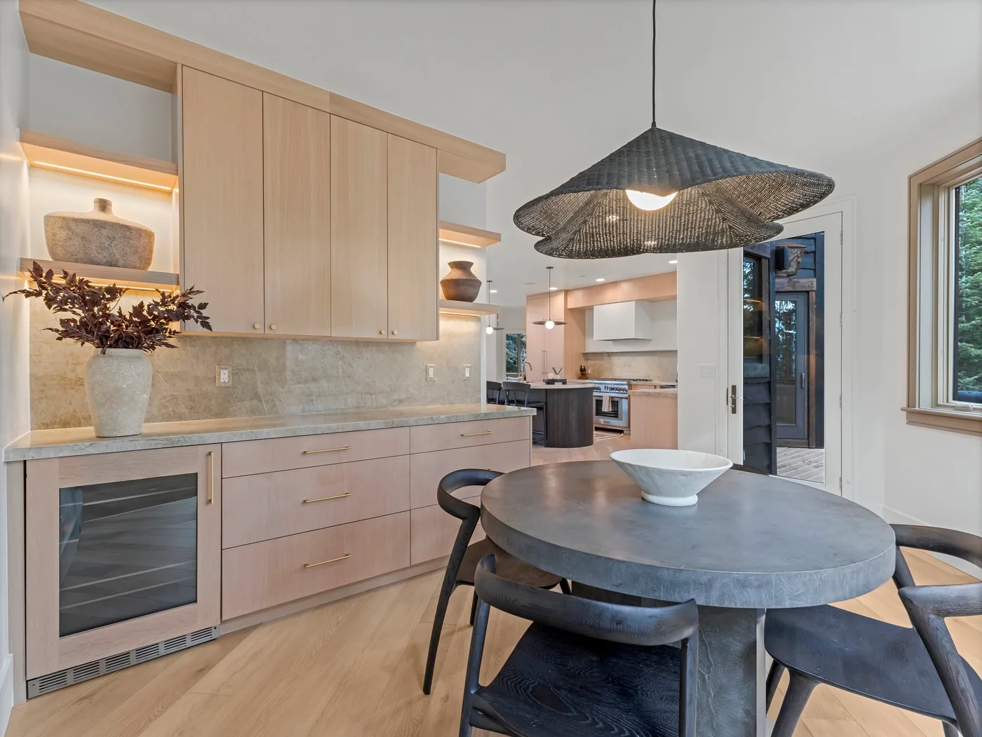 A modern kitchen and dining area with light wood cabinetry and a round table.