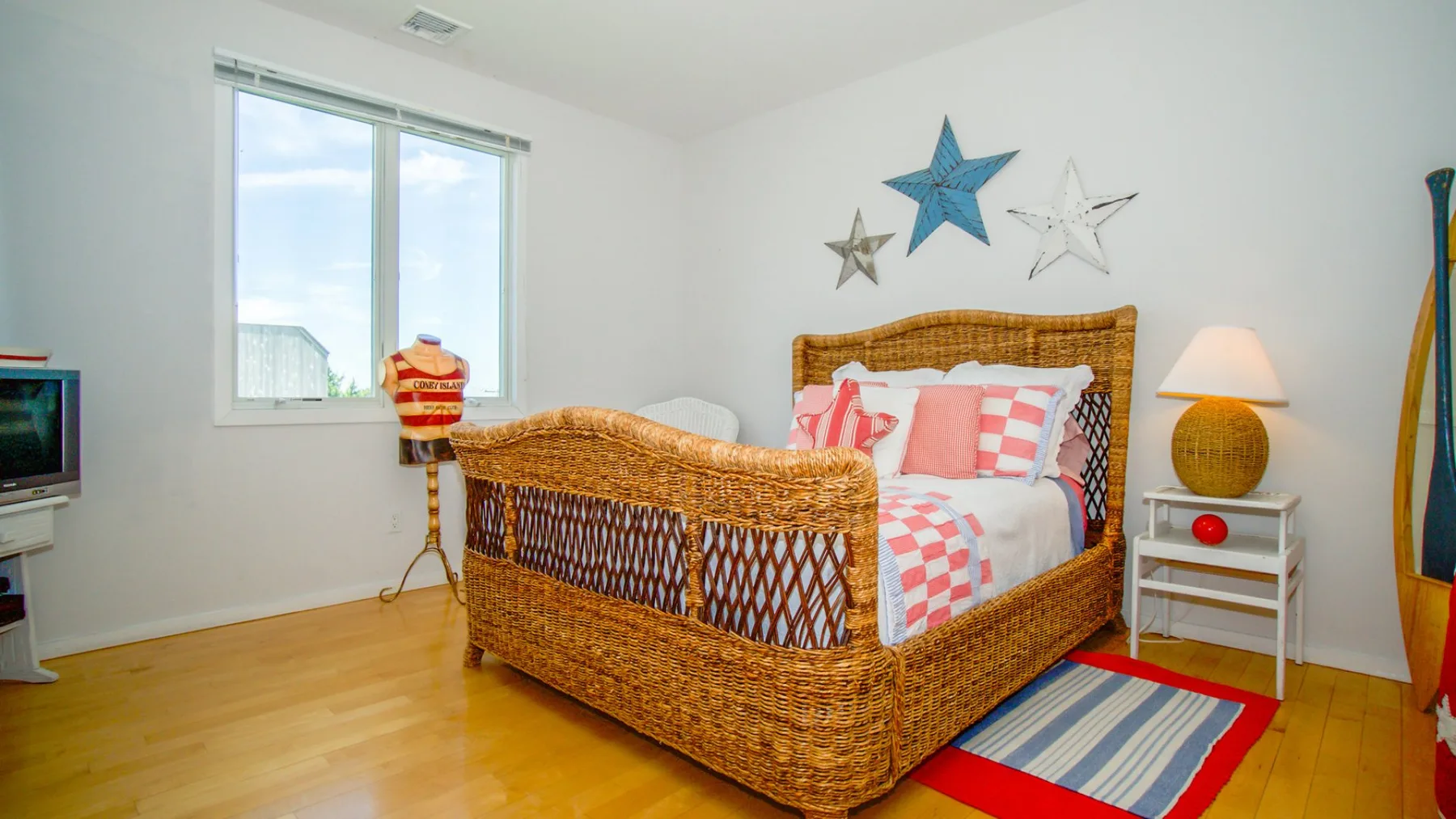 Un dormitorio con una cama tejida, ropa de cama colorida y estrellas decorativas en la pared.