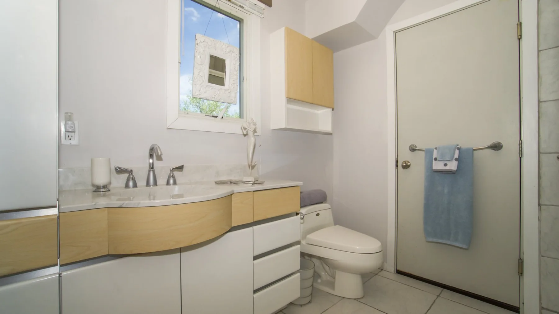 Un baño con lavabo, inodoro y una toalla colgada en la puerta.