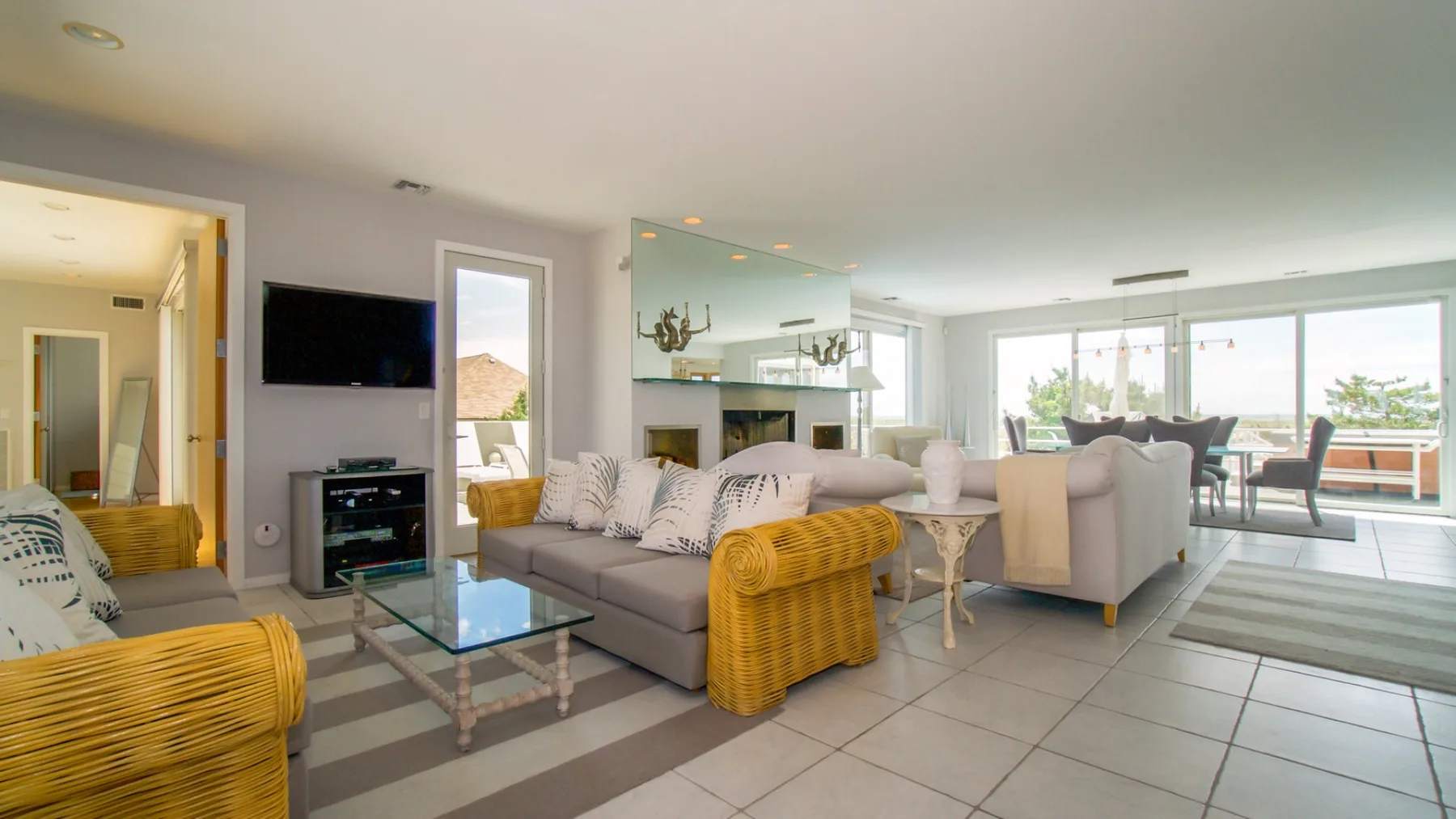 A bright living room opens onto a dining area beside large windows.