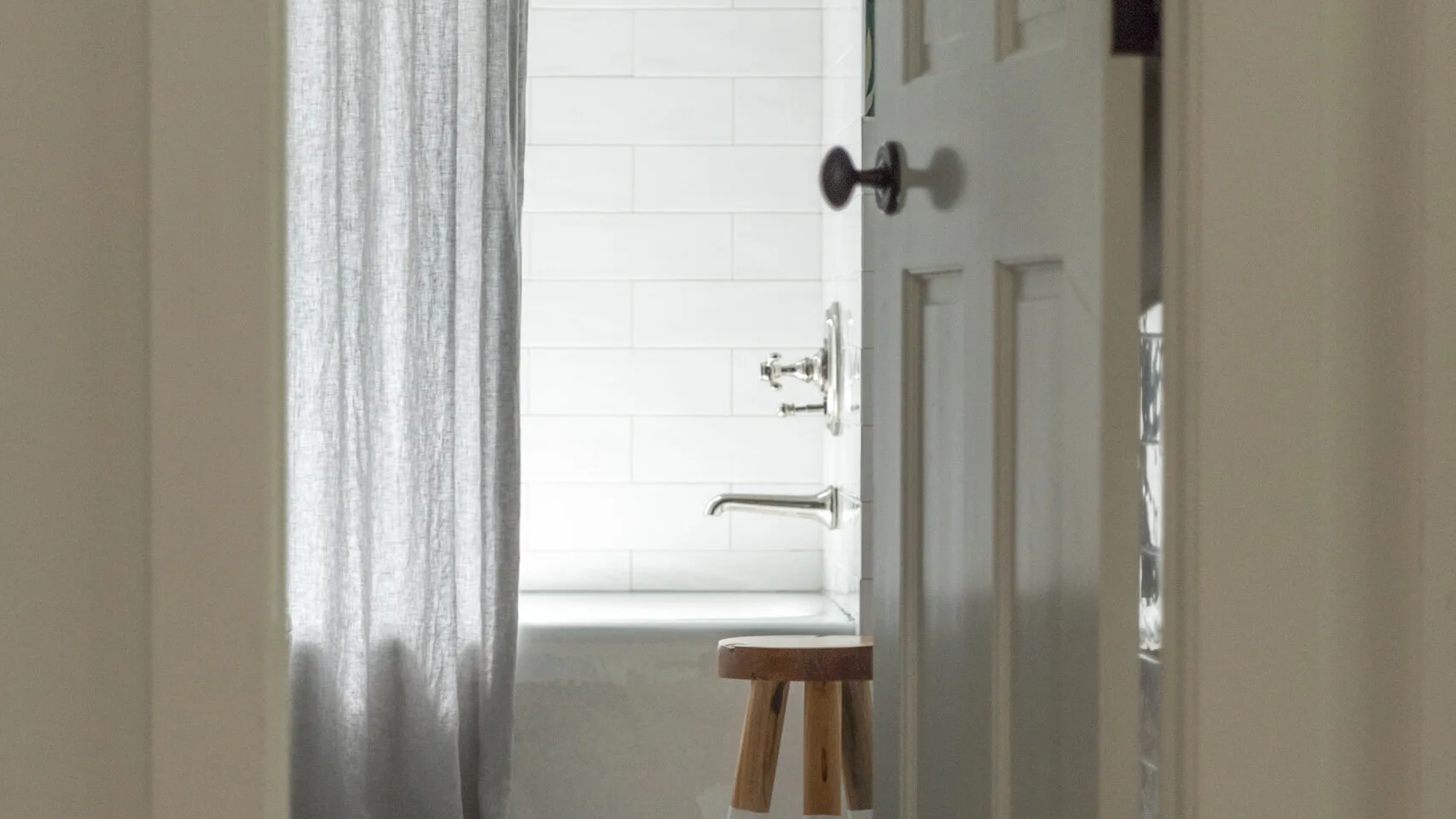 Un baño con bañera, azulejos blancos y una cortina de ducha.