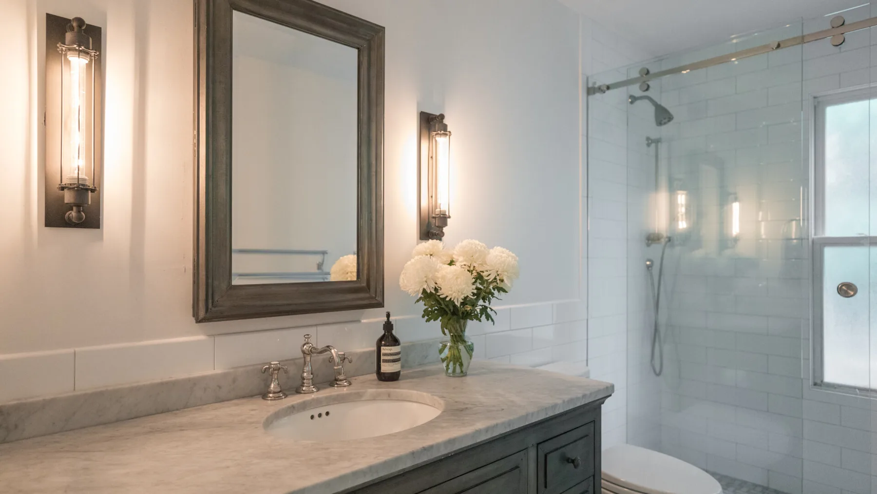 Un lavabo de baño con flores junto a una ducha de vidrio.