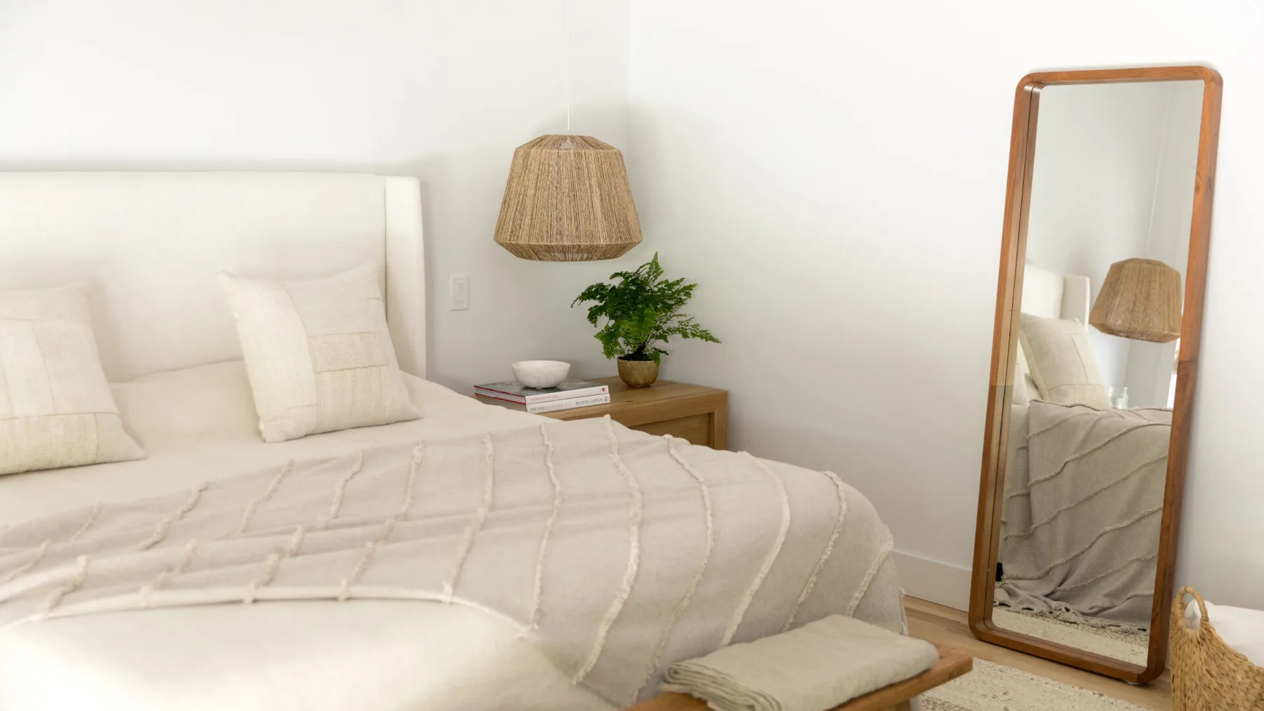 Un dormitorio luminoso con una cama bien tendida y un espejo de cuerpo entero.