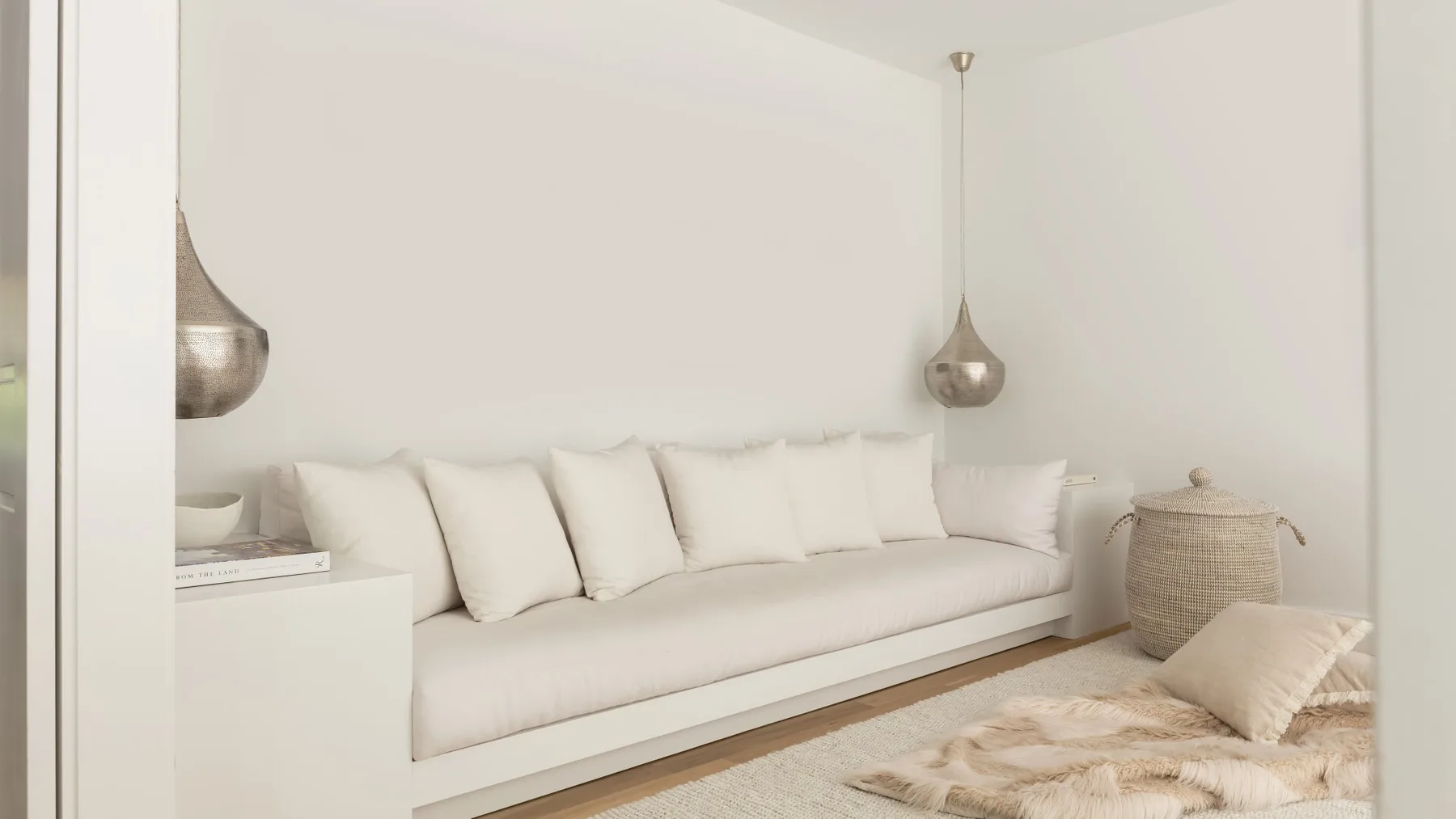 Una sala luminosa con un sofá largo y claro y cojines.