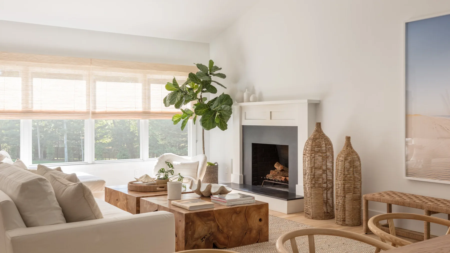Una sala luminosa tiene asientos neutros, una mesa de centro de madera y una chimenea.