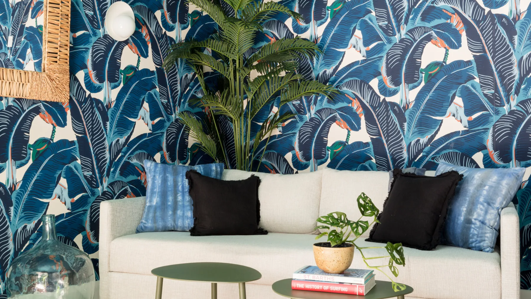 Una zona de estar está frente a un papel tapiz con motivos tropicales.