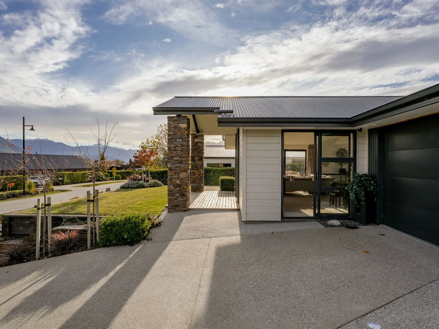 An exterior view of a modern house with a driveway and landscaped garden.