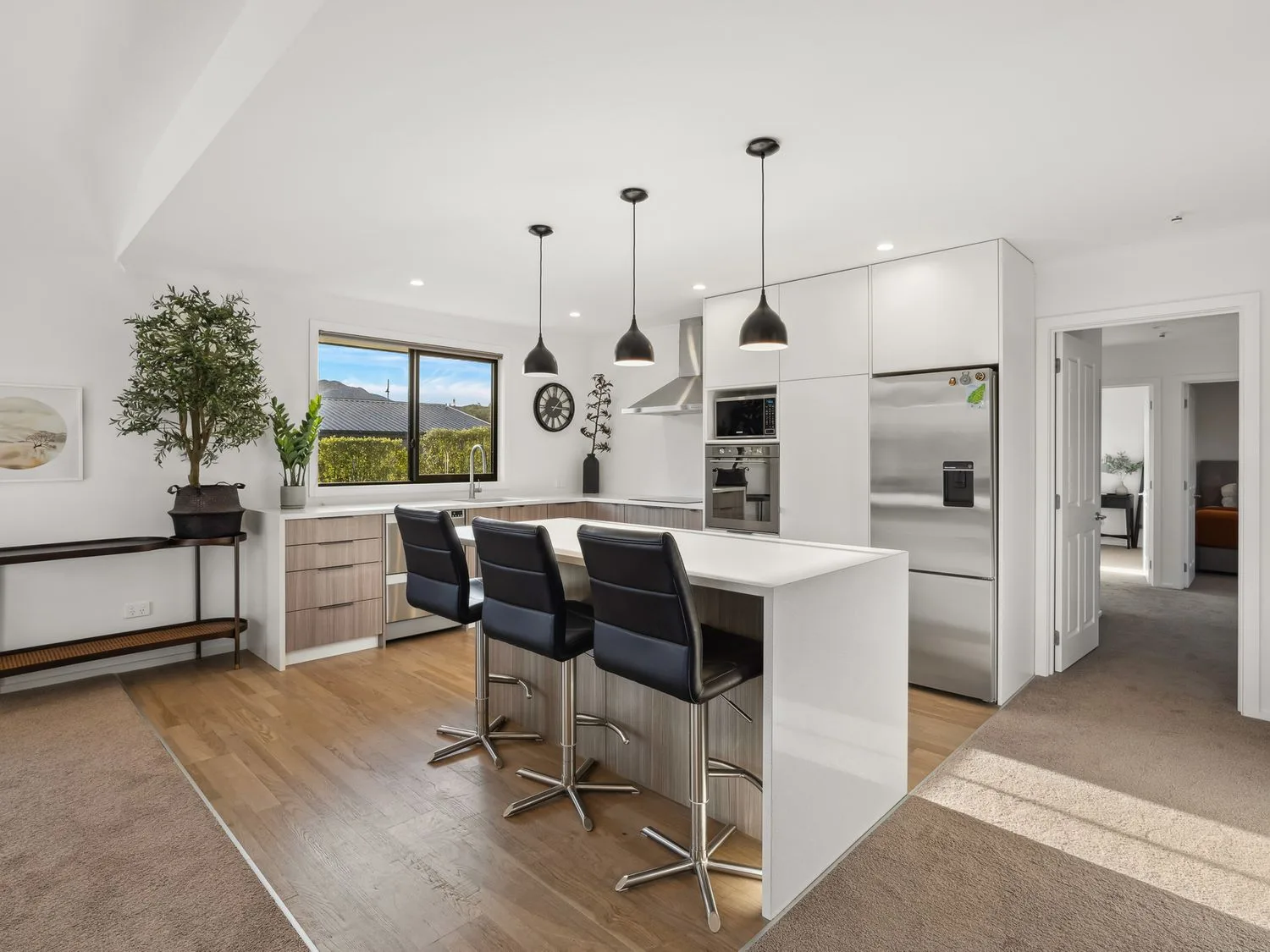 A modern kitchen with a large island and dark seating.