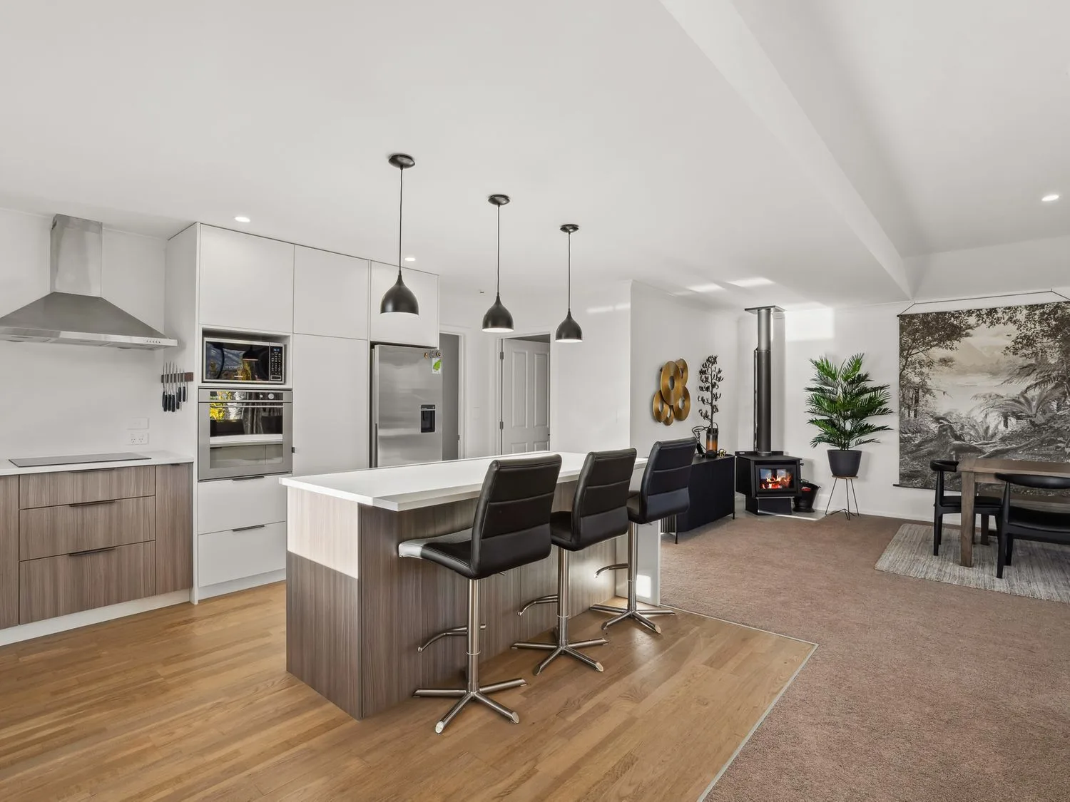 A kitchen with bar stools and a dining table at Mako Haven - Mountain Outlook Wanaka
