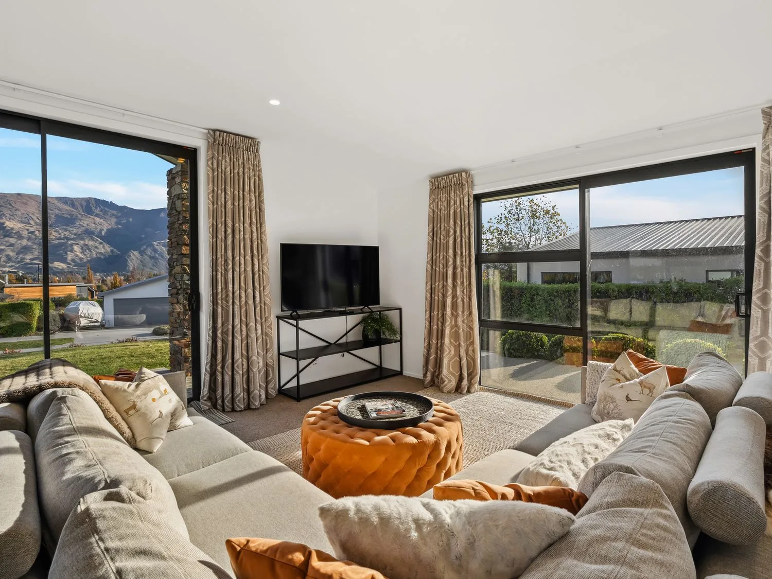 Una sala de estar con un sofá y un televisor en Mako Haven - Mountain Outlook, en Wanaka