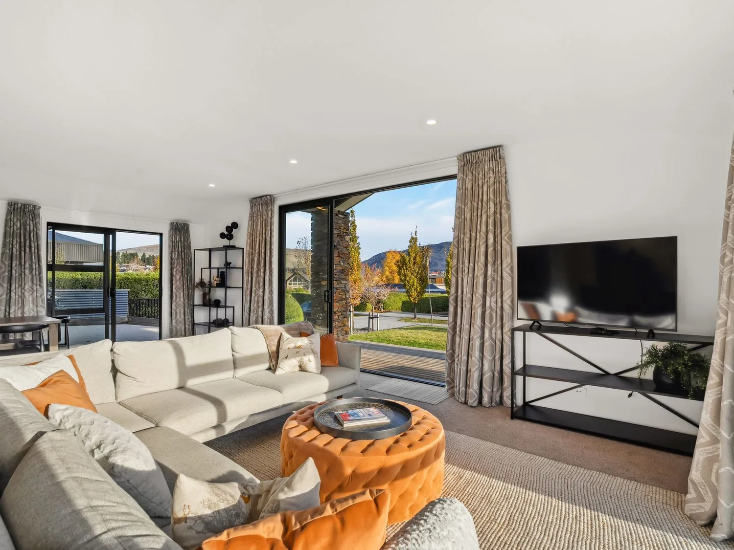 A bright living room with seating, a round coffee table, and large windows.