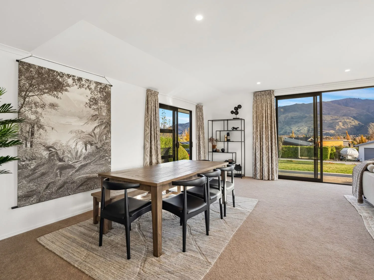A bright dining area with a wooden table and wide windows overlooking the mountains.