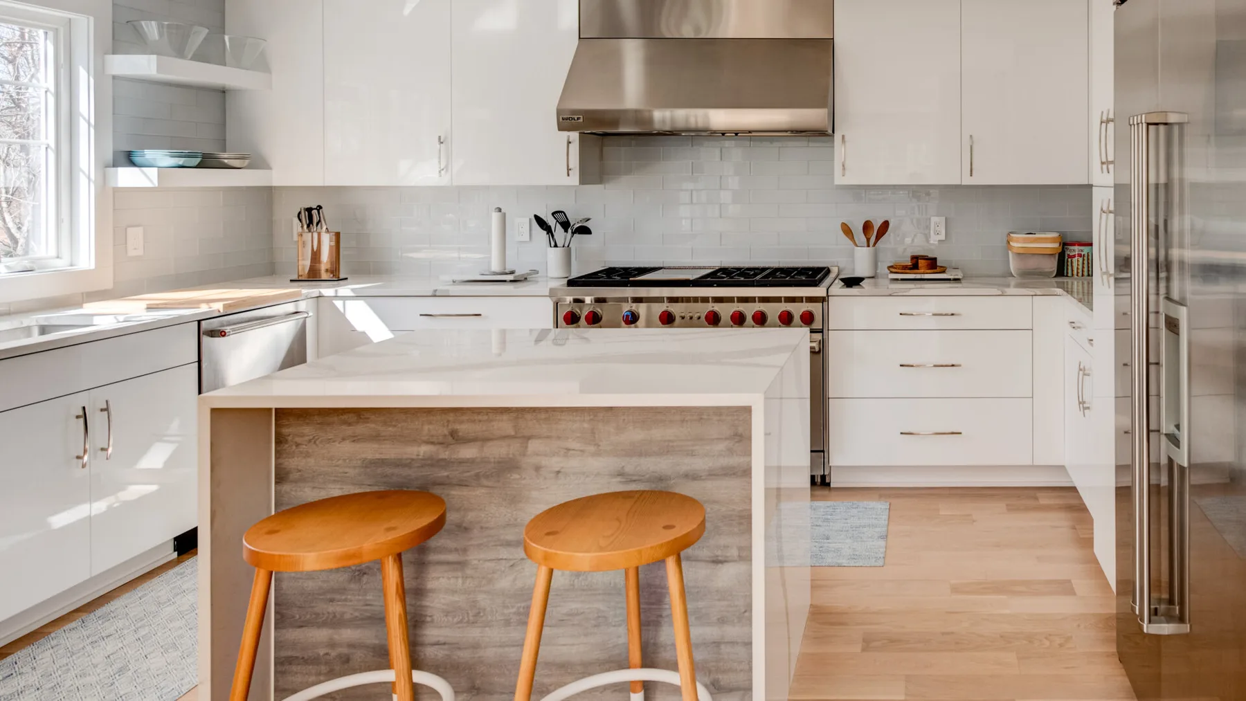 Una cocina luminosa con gabinetes blancos, una estufa y una isla de madera con asientos.
