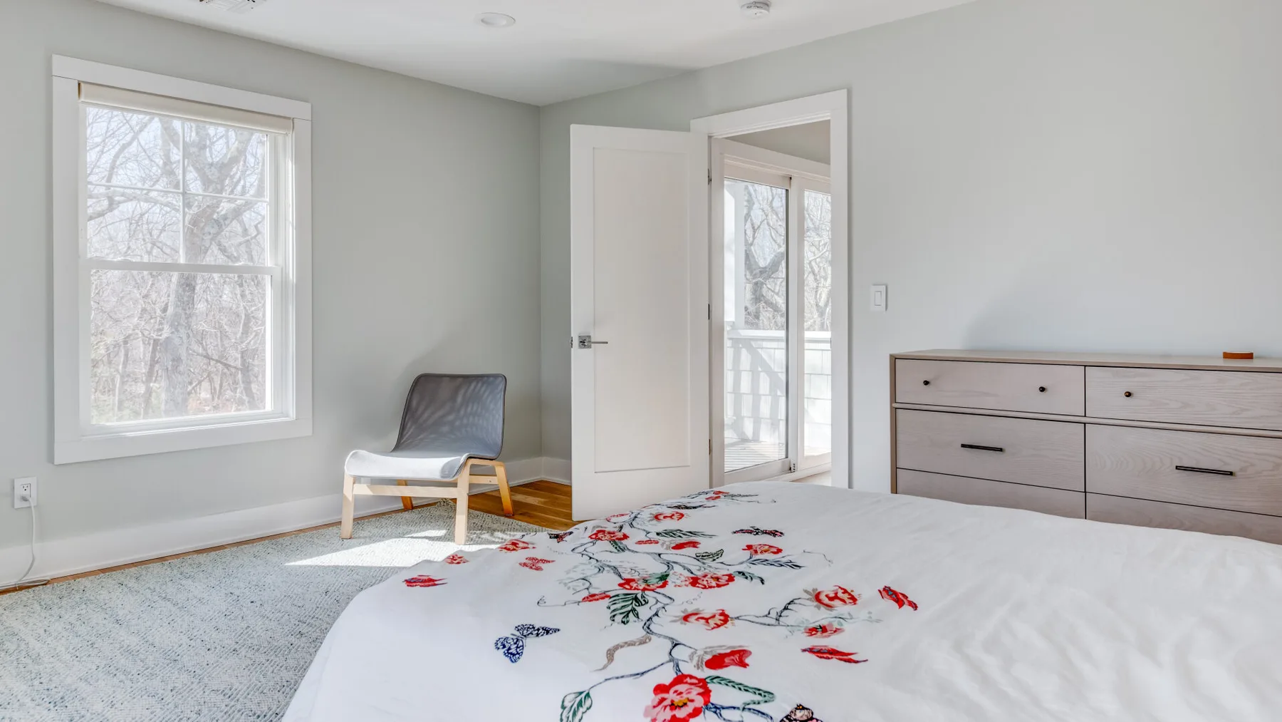 Un dormitorio luminoso con una cama cubierta por una colcha de estampado floral.